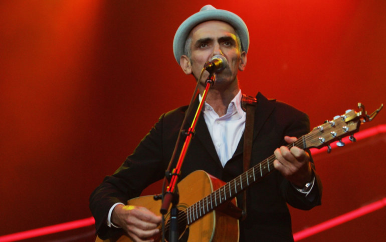 Paul Kelly performing on stage with a guitar