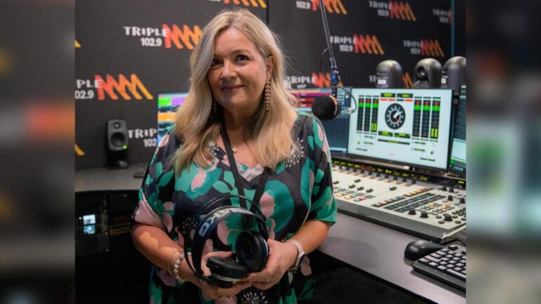 Tanya holding her headphones in Triple M radio studio.