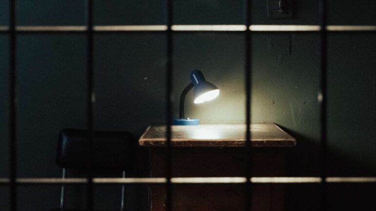 Prison cell with desk and lamp