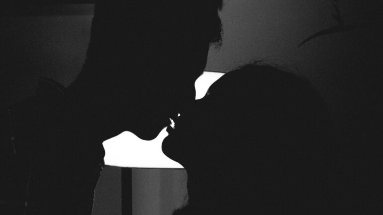 Silhouette of man and woman kissing.