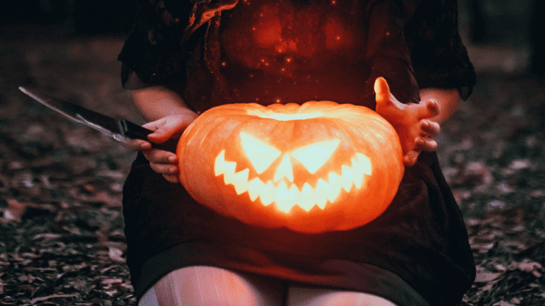 Woman holding Halloween pumpkin and a knife
