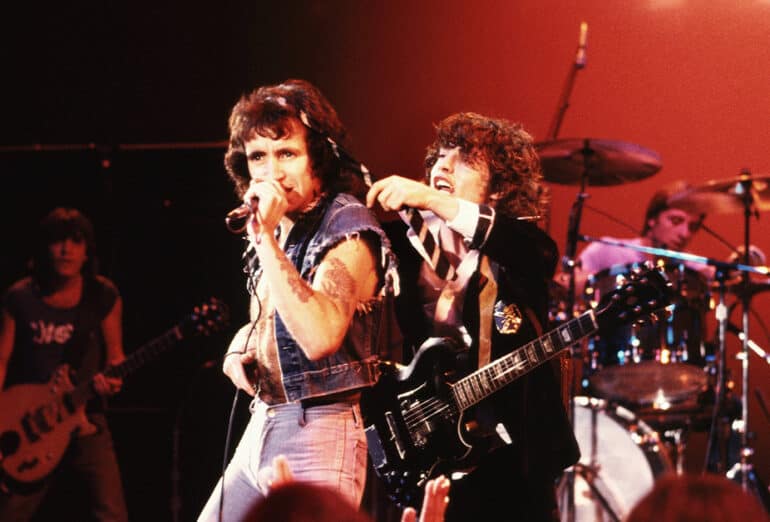 Singer Bon Scott and guitarist Angus Young of AC/DC put on a show for the crowd circa 1977 in Hollywood, California. In the background can be seen rhythm guitarist Malcolm Young and drummer Phil Rudd.
