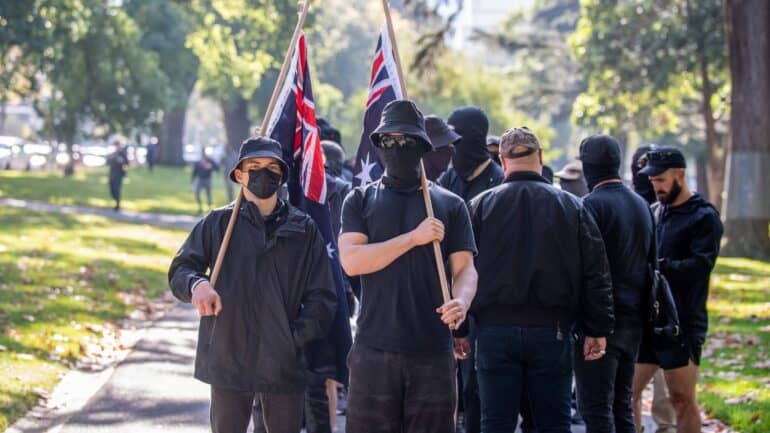 MELBOURNE, AUSTRALIA - 2023/05/13: Neo-Nazis protesters with flags salute as they are ordered to leave the area during the demonstration.